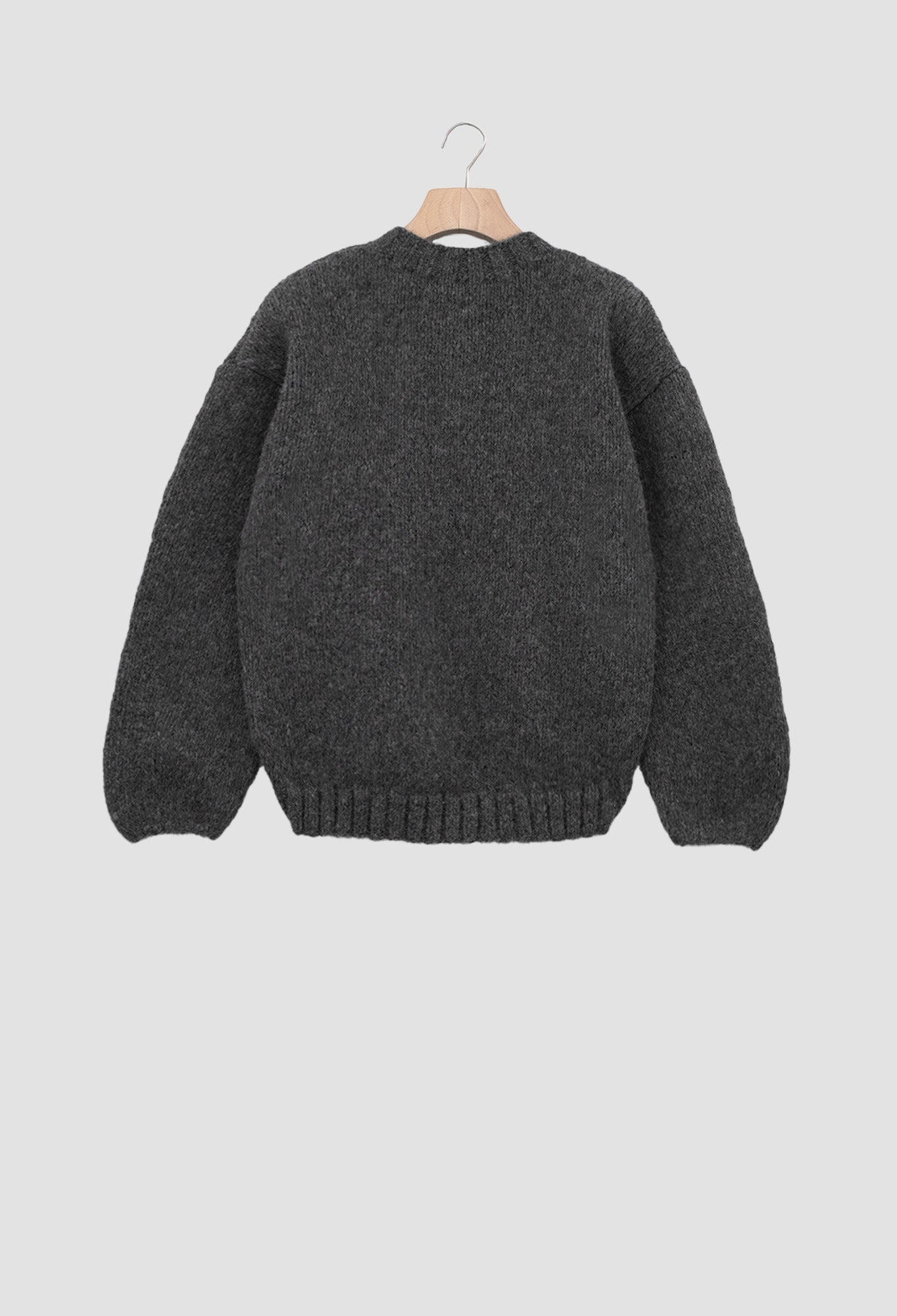 Dark gray sweater on a hanger against a light gray background