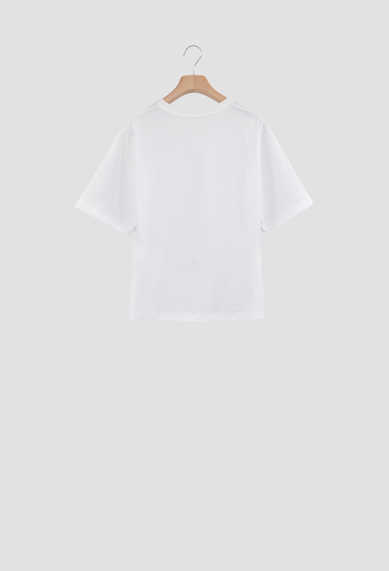 White t-shirt on a wooden hanger against a light gray background