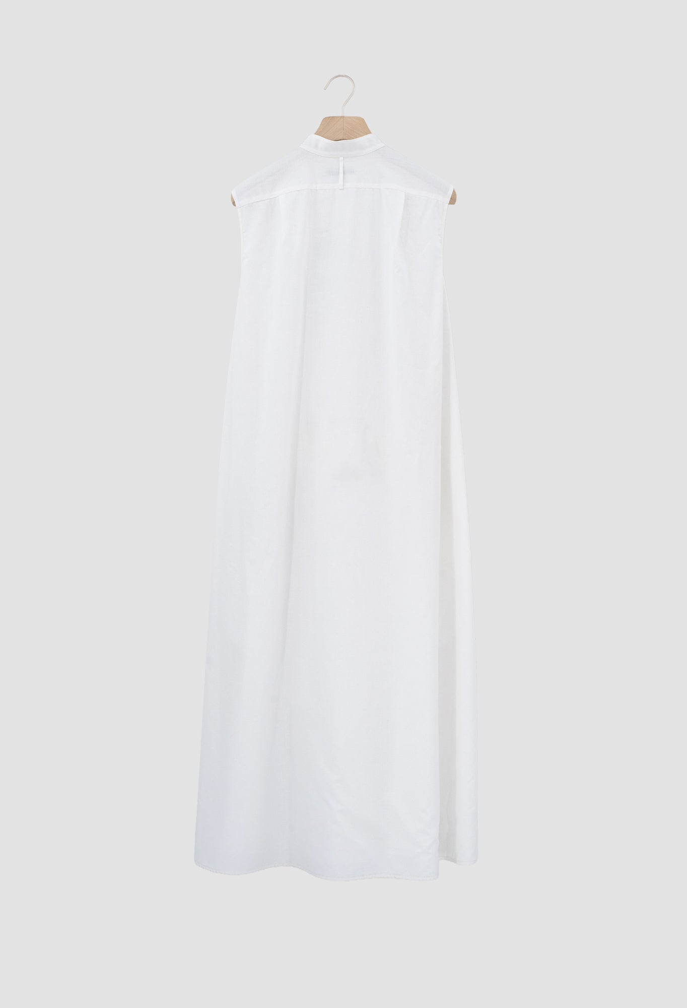 Ivory Sleeveless cotton batiste dress with asymmetrical hem and metal button closures.