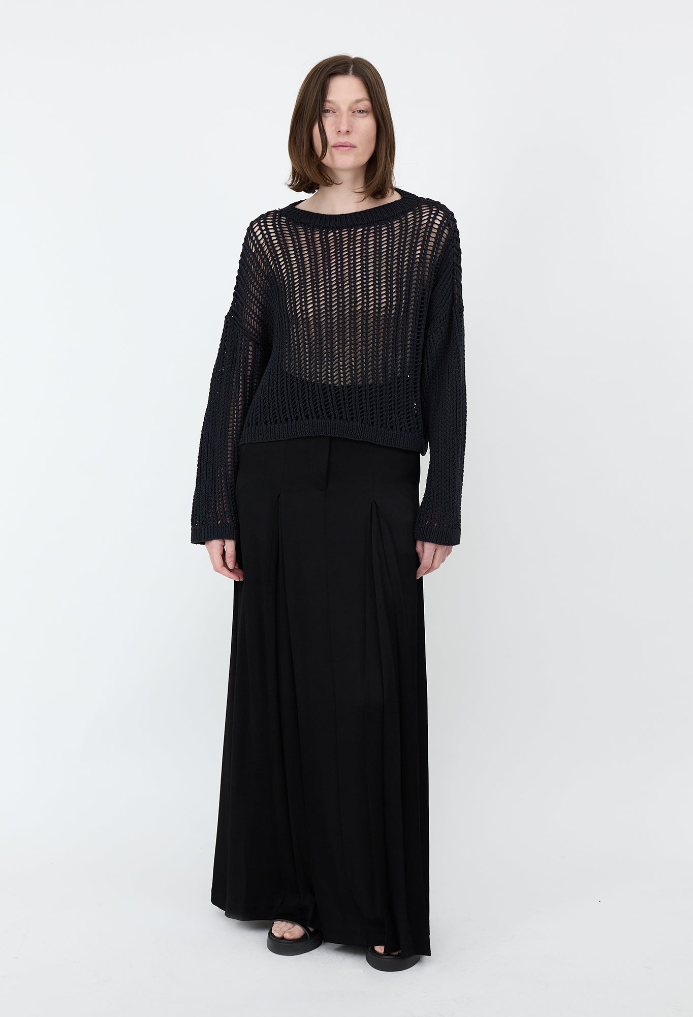 Woman wearing a black outfit with a sheer top on a white background