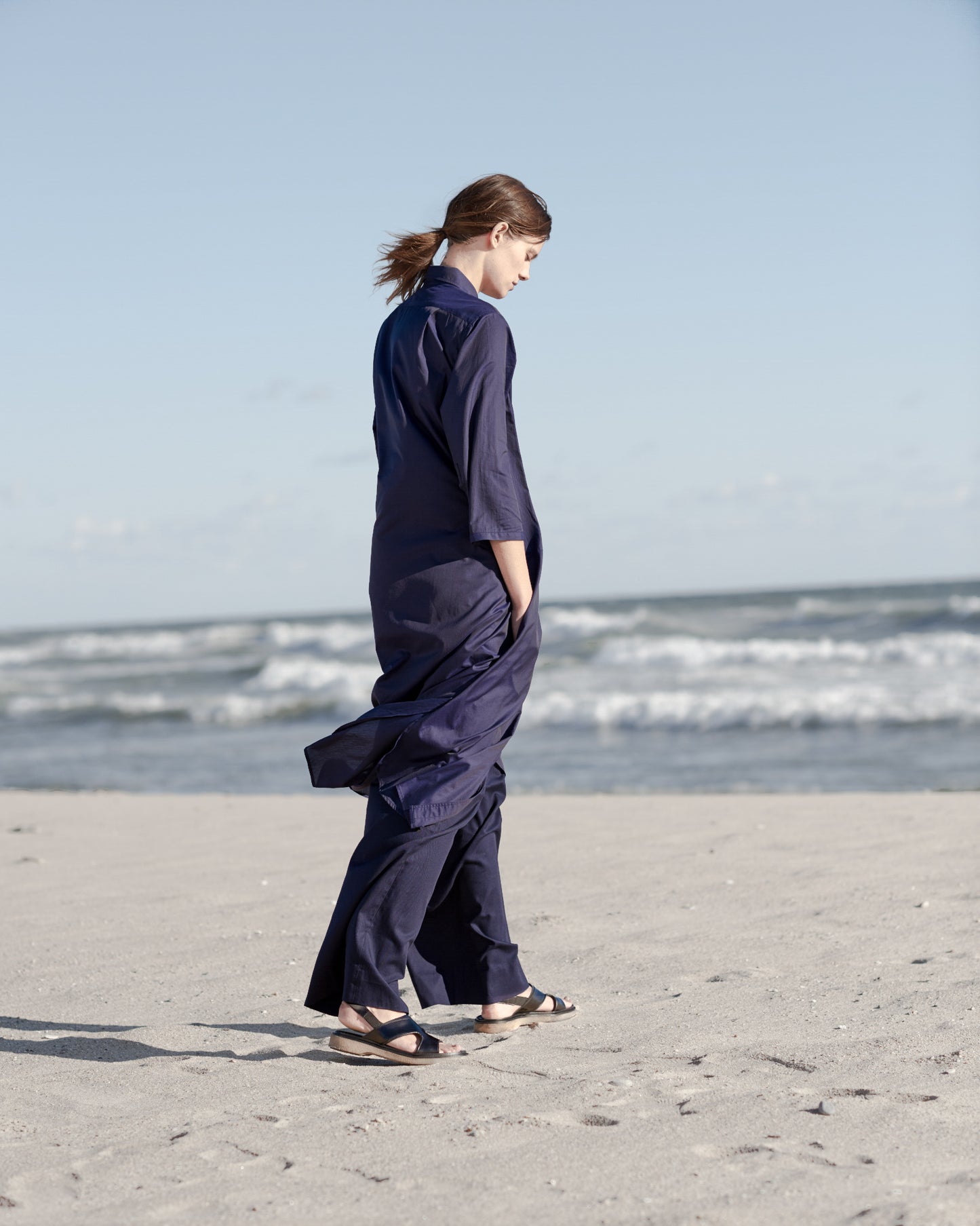 Penelope - A navy blue, long, lightweight shirt dress with a collar and buttons down the front on the beach