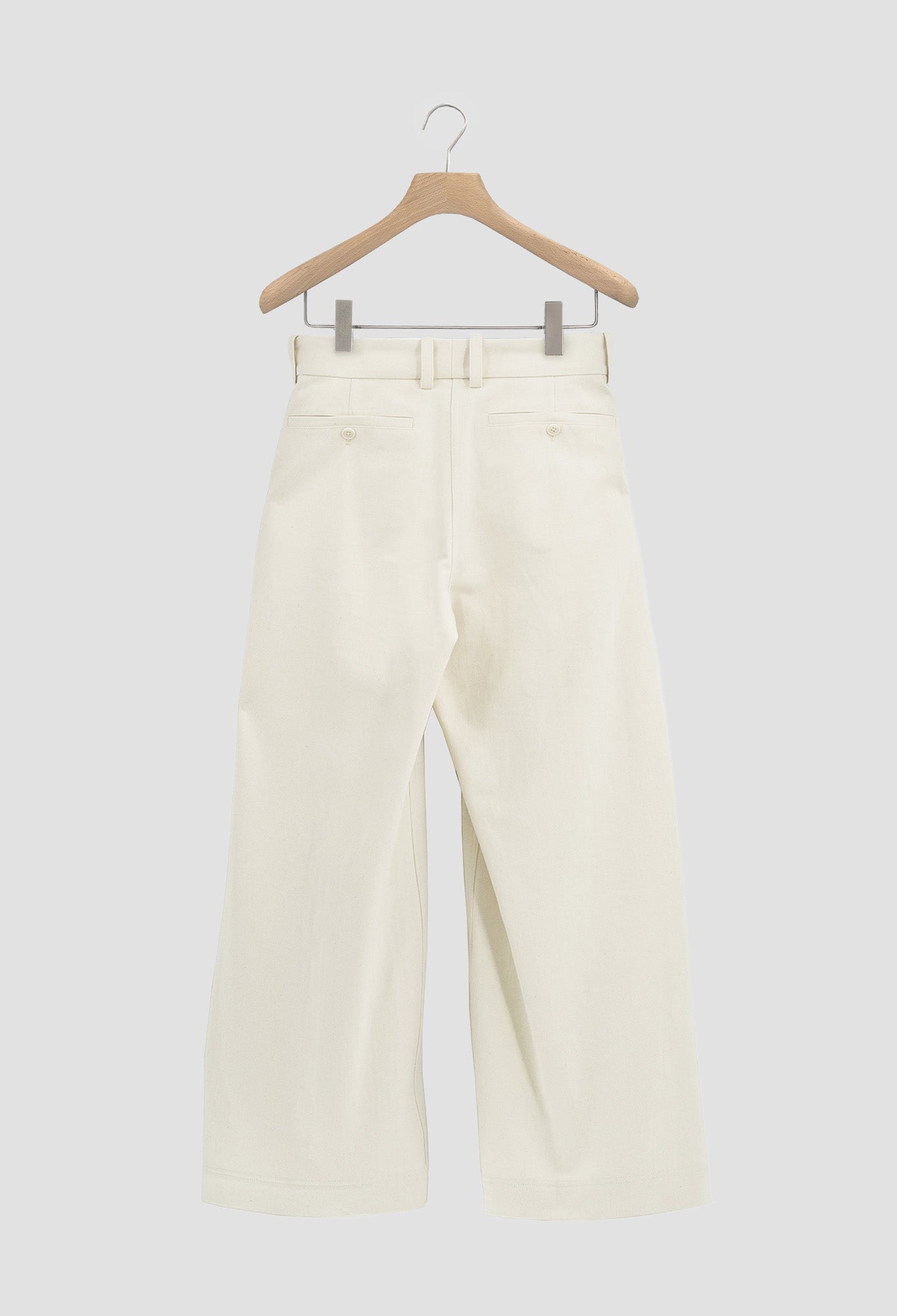 White pants on a wooden hanger against a white background