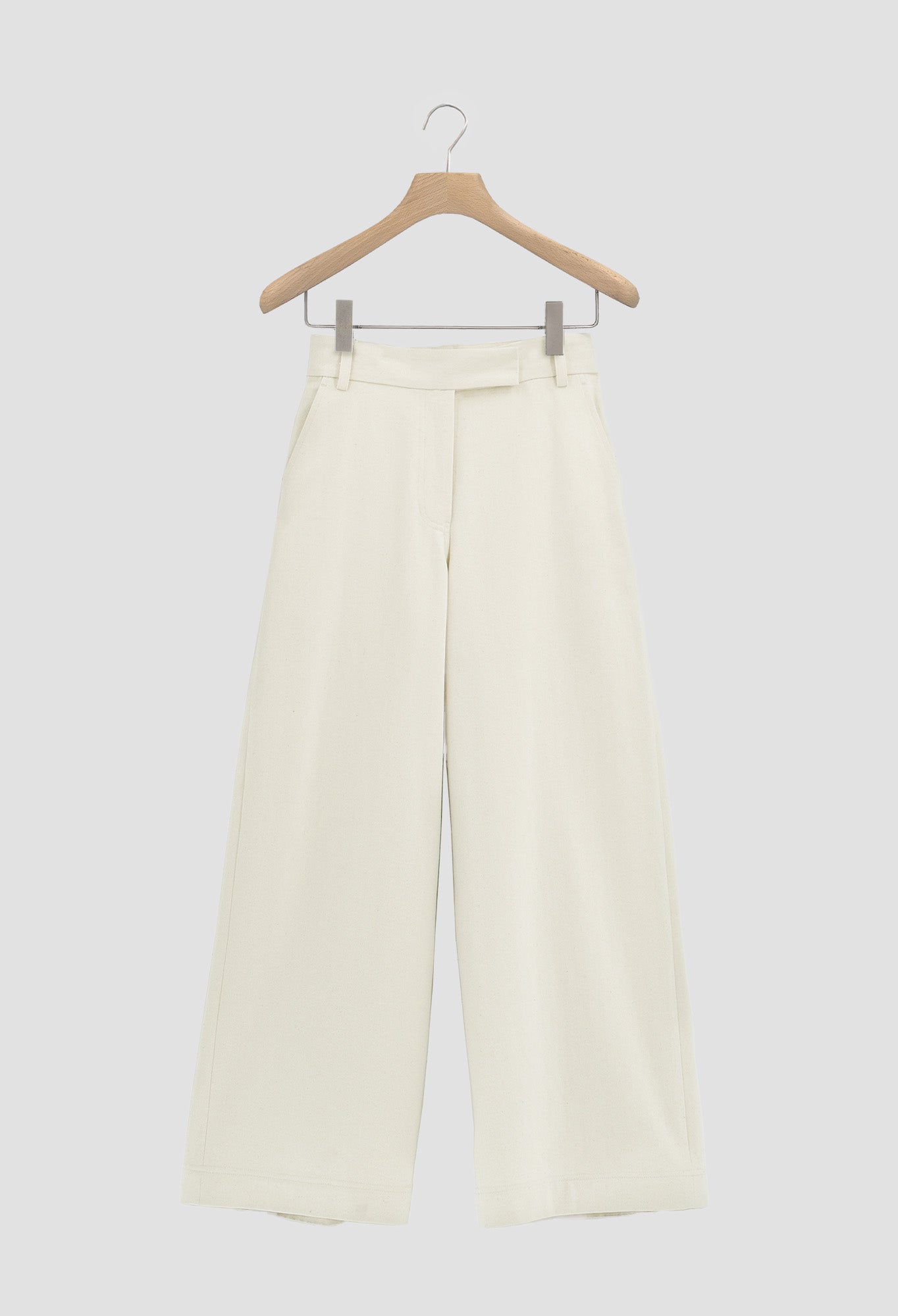 White pants on a wooden hanger against a white background