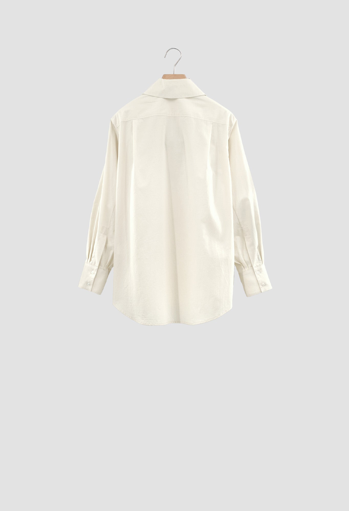 White shirt on a hanger against a light gray background