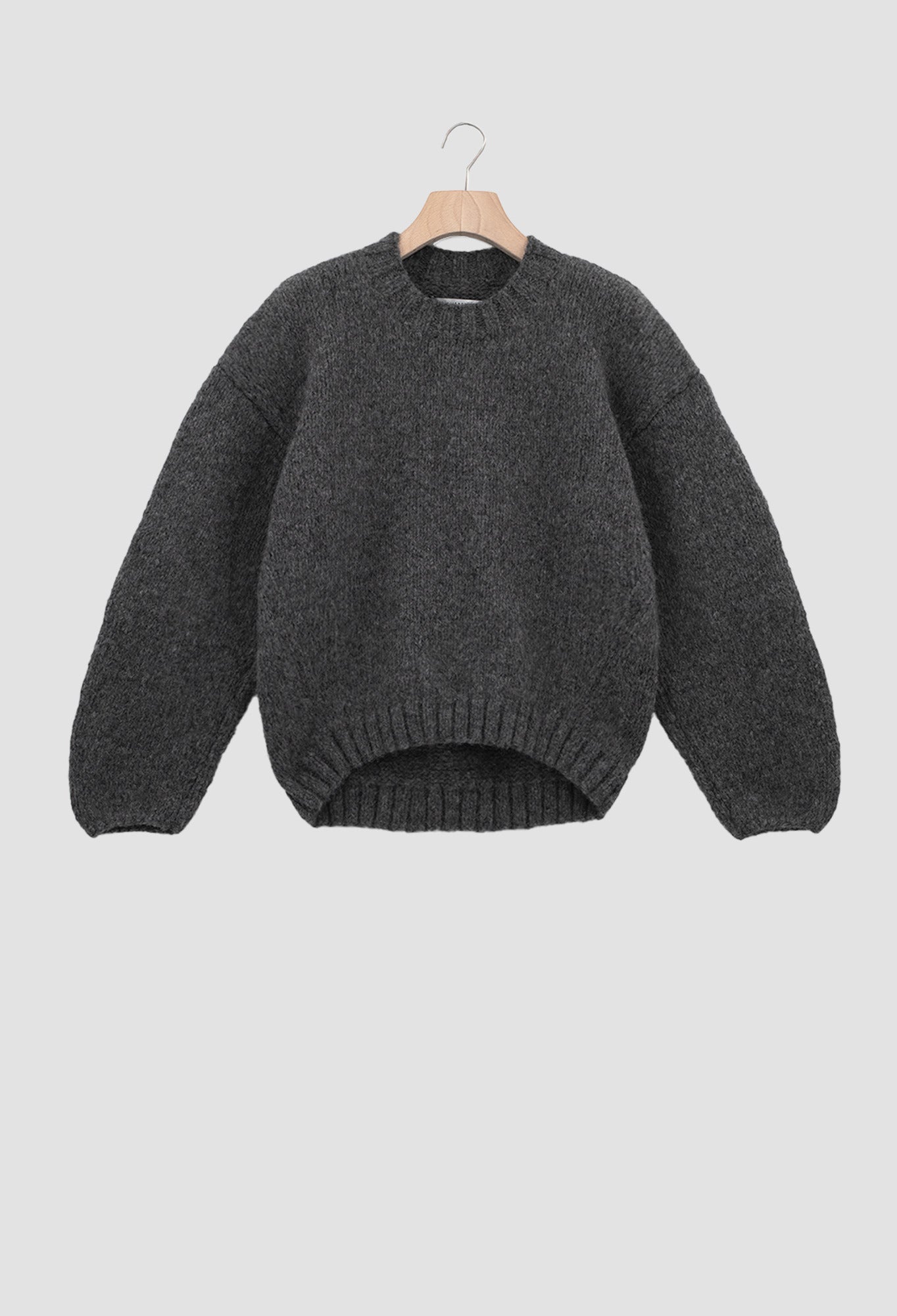 Gray sweater on a hanger against a light gray background