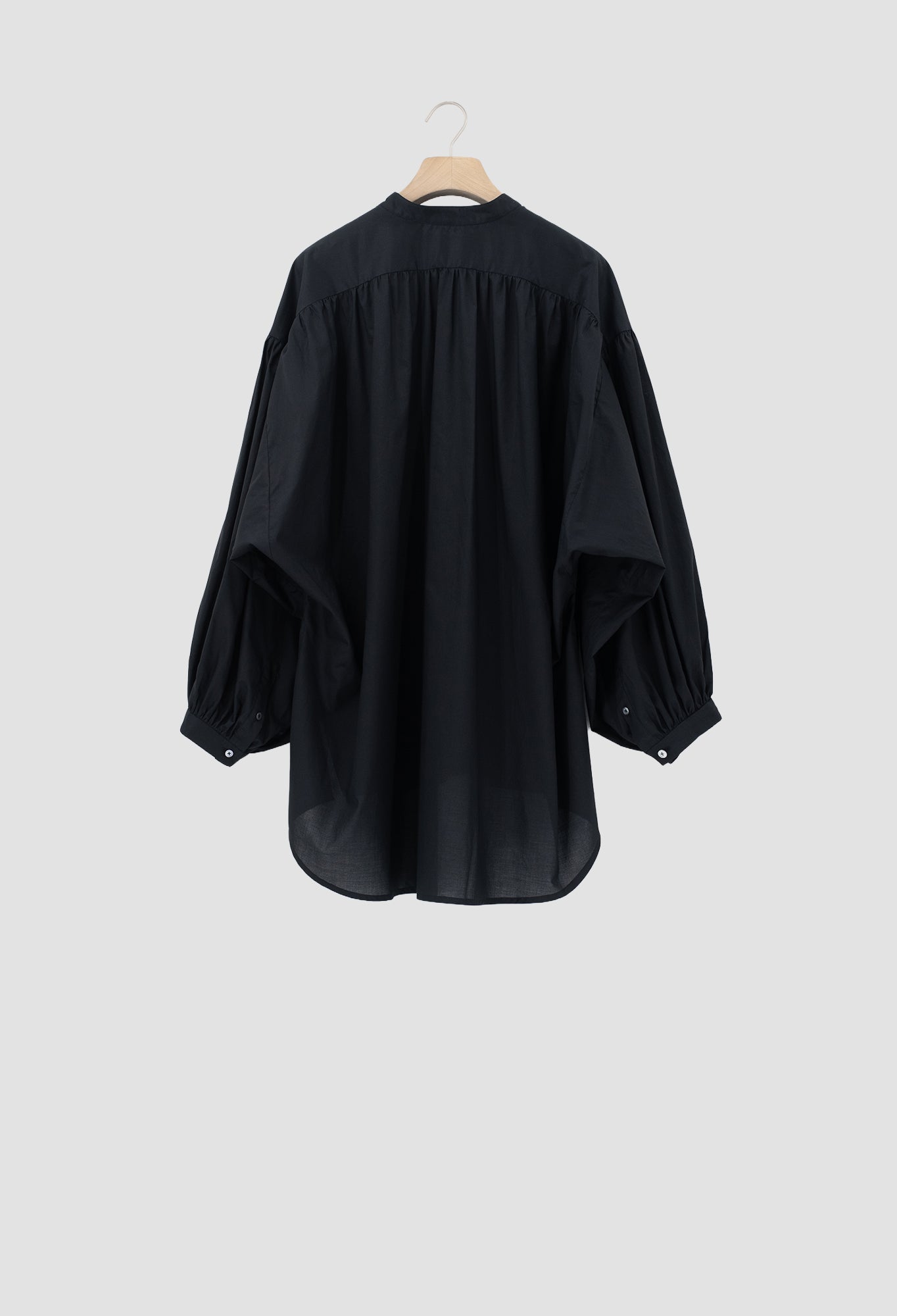 A black long-sleeve blouse with a gathered, balloon-like sleeve design and a high neckline, hanging on a wooden hanger against a light gray background.
