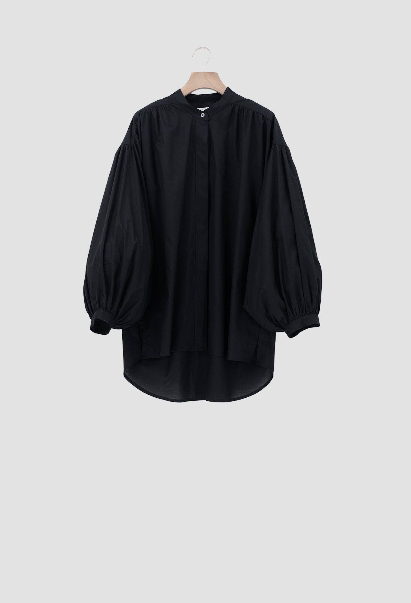 A black long-sleeve blouse with voluminous balloon sleeves and a high round neckline, hanging on a wooden hanger against a light gray background.