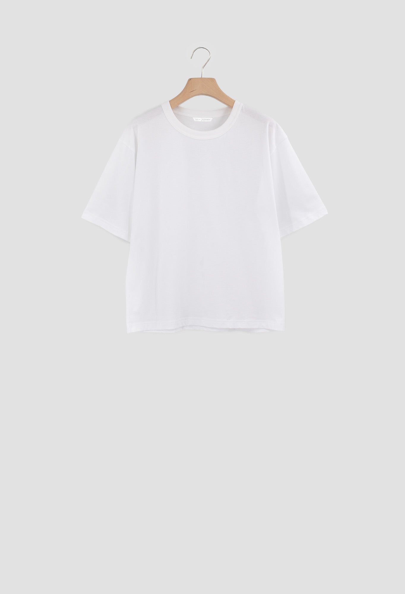White t-shirt on a wooden hanger against a white background