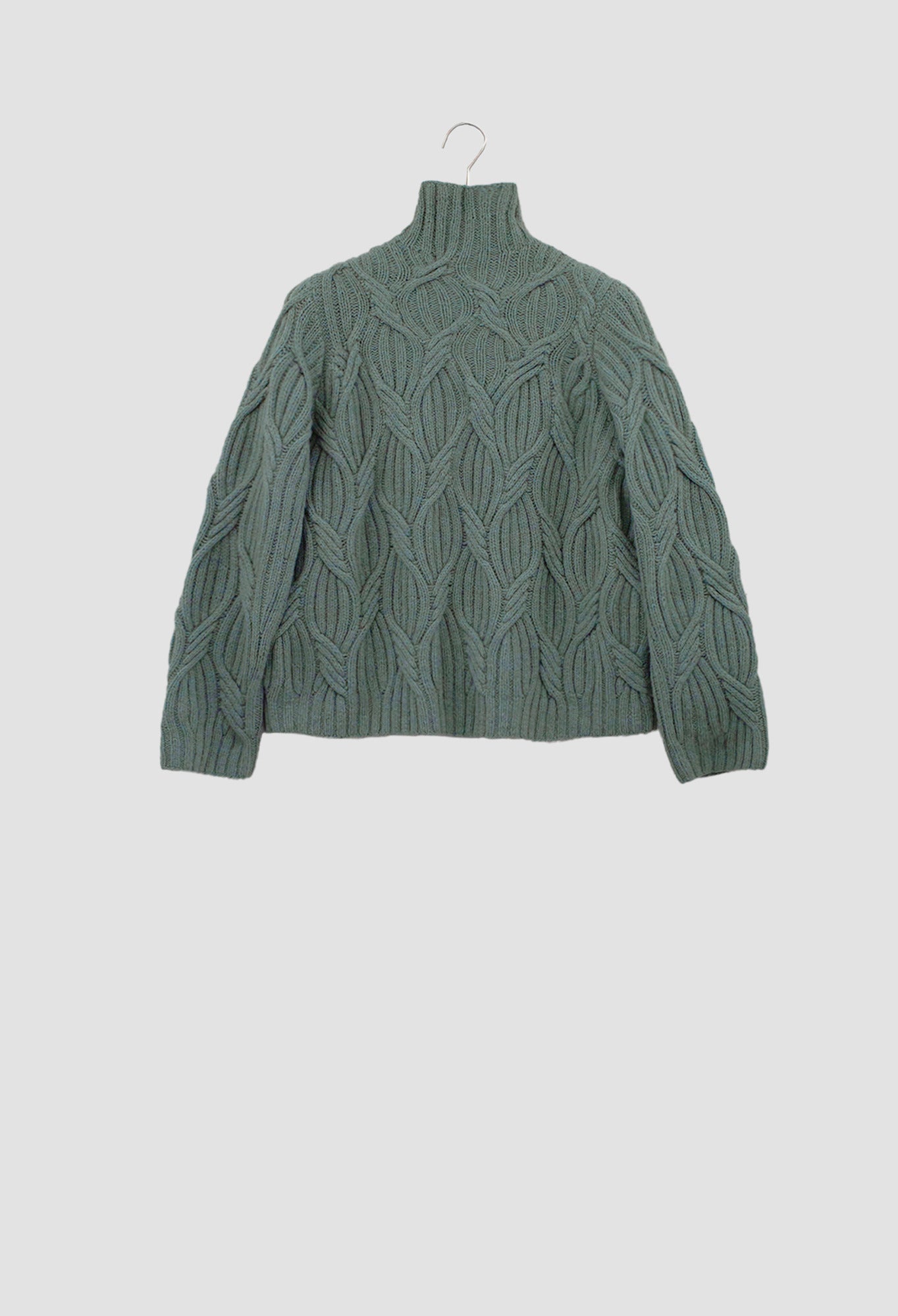 Green cable knit sweater on a hanger against a light gray background