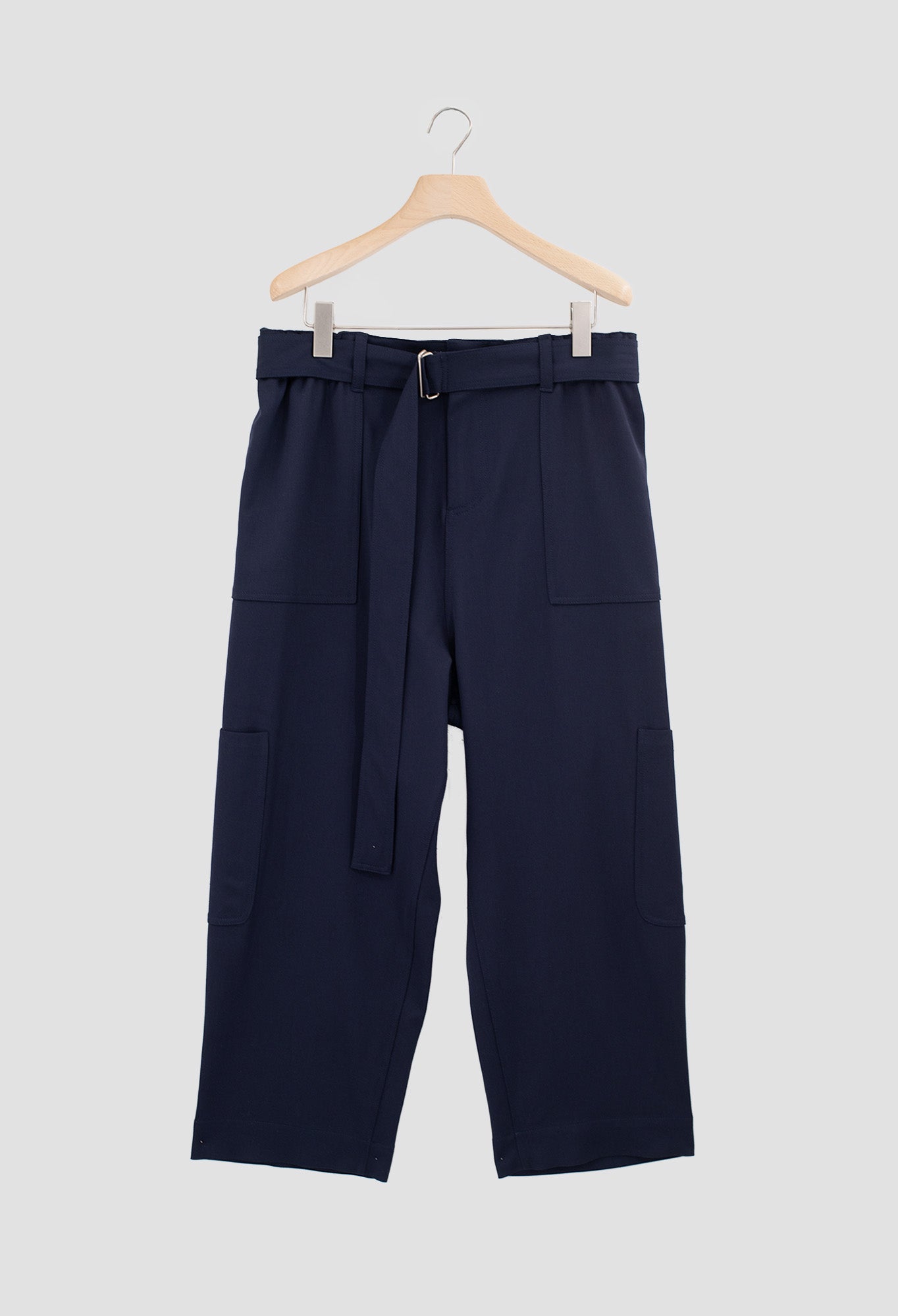Navy blue pants with a belt on a hanger against a light gray background