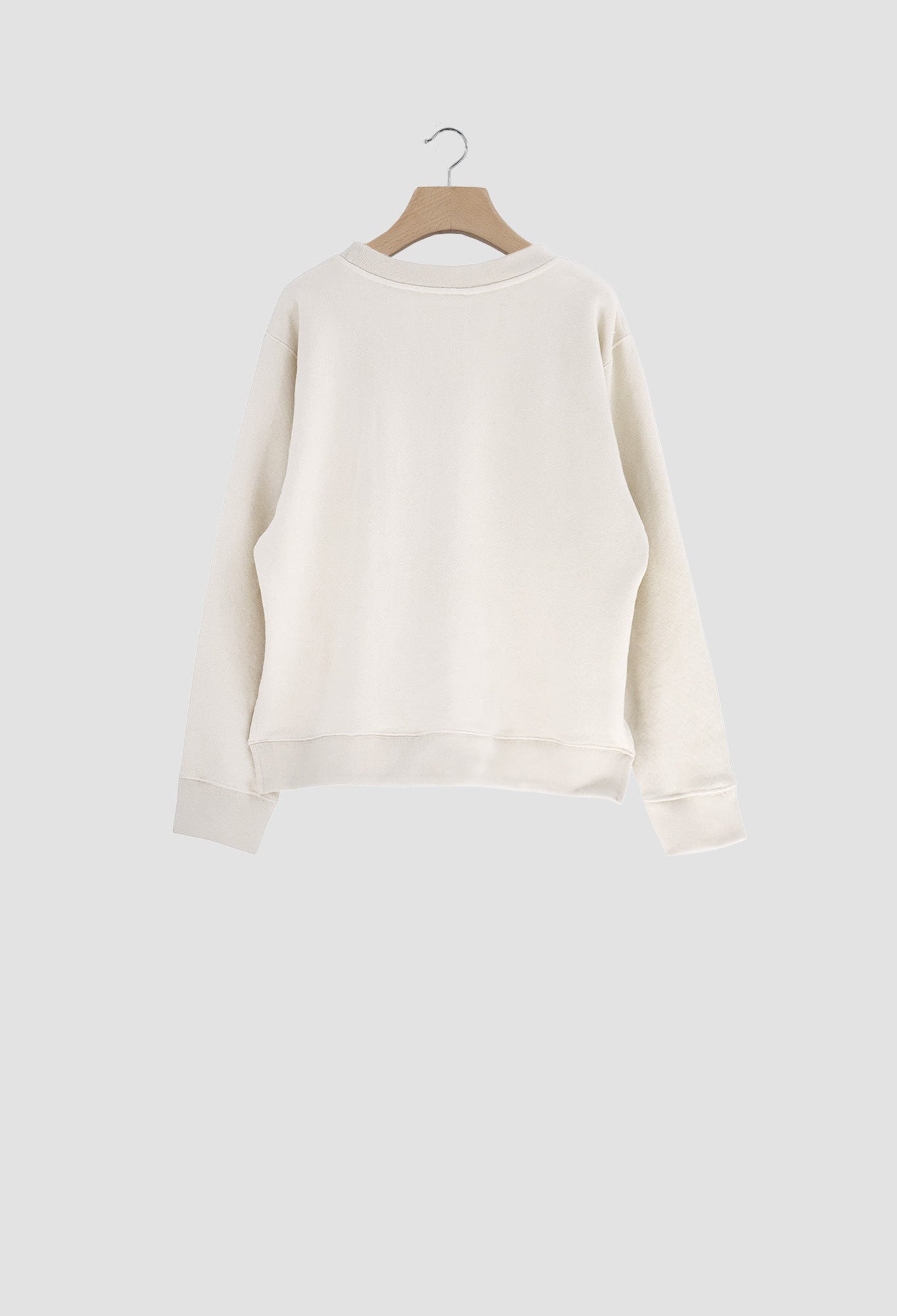 White sweater on a wooden hanger against a light gray background