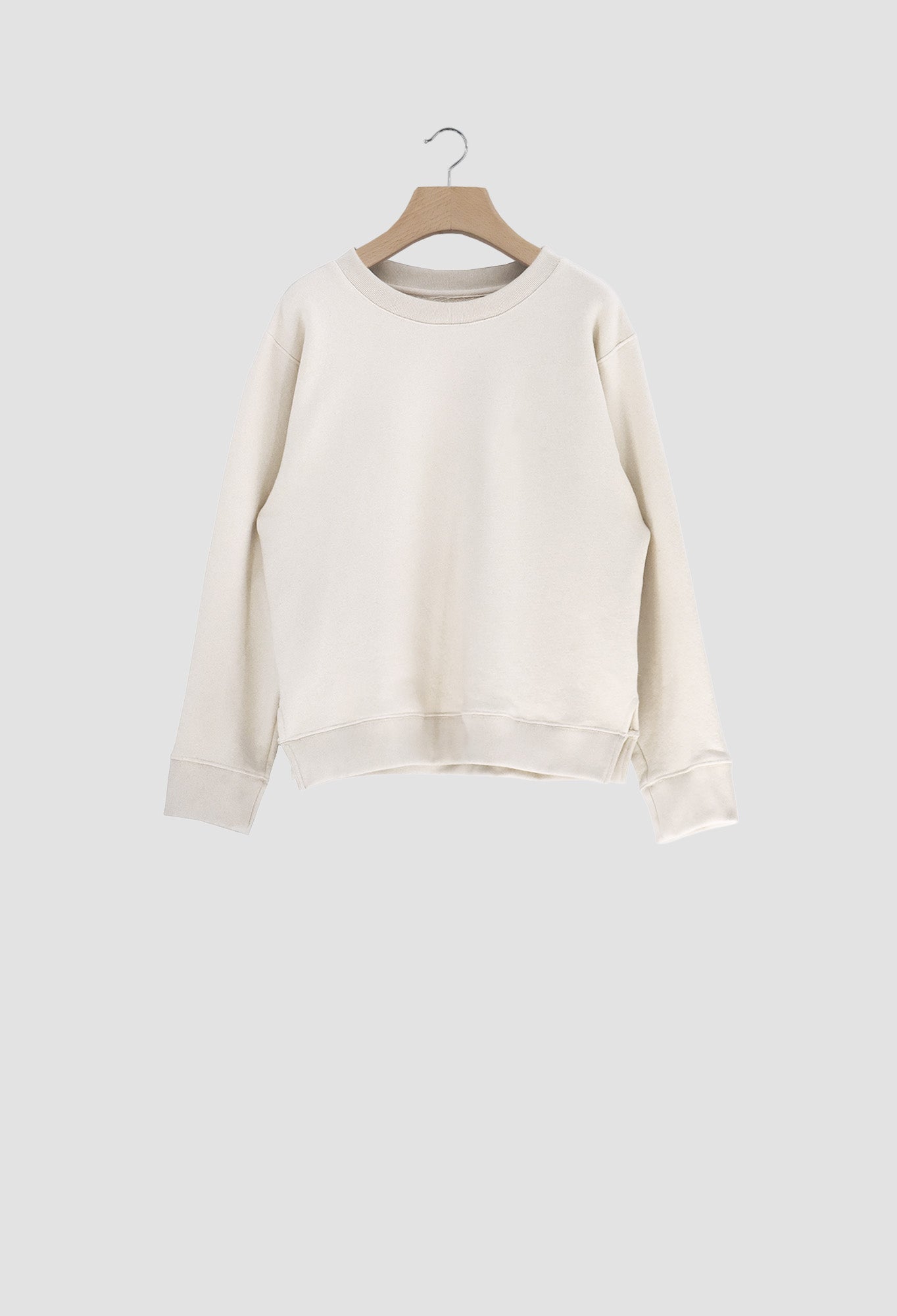 White sweater on a wooden hanger against a light gray background