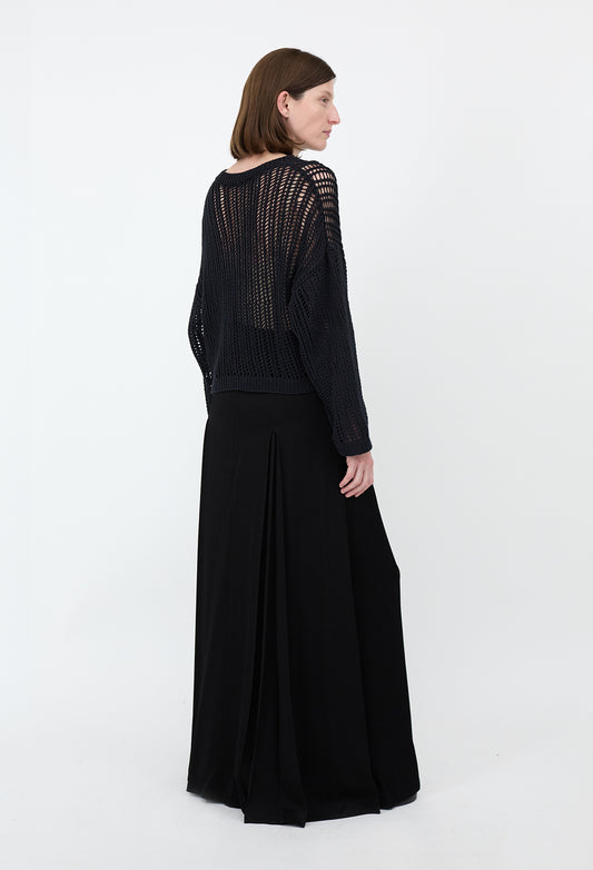 Woman wearing a black dress with intricate detailing on a white background