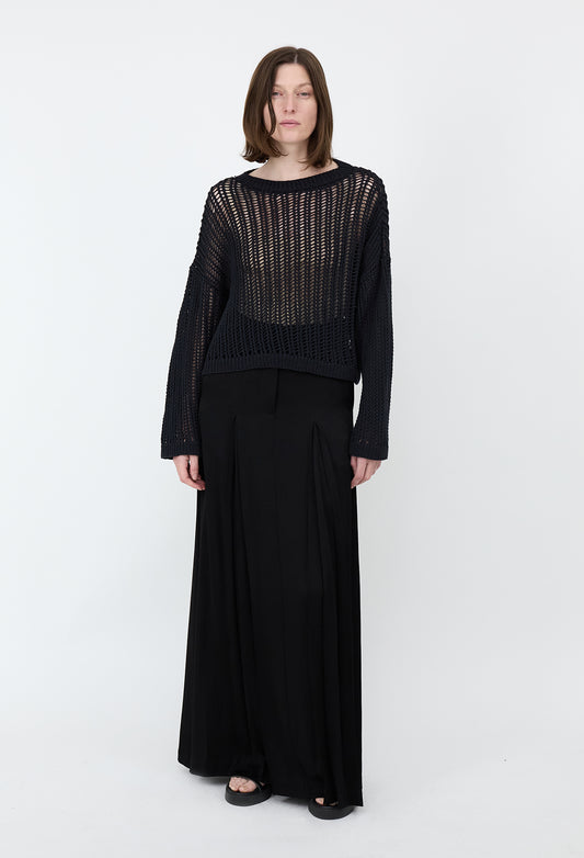 Woman wearing a black outfit with a sheer top on a white background