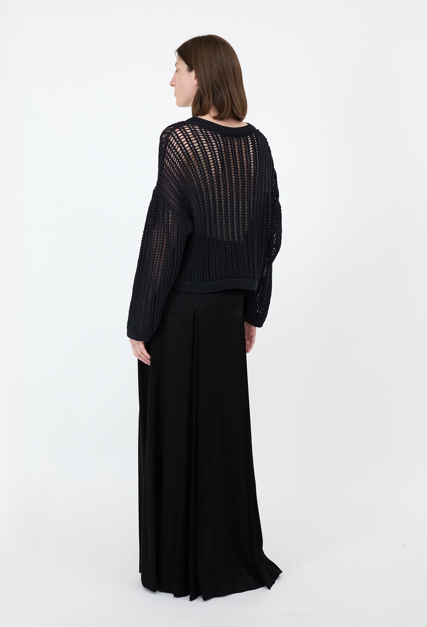 Woman wearing a black dress with a textured top and flowing skirt on a white background