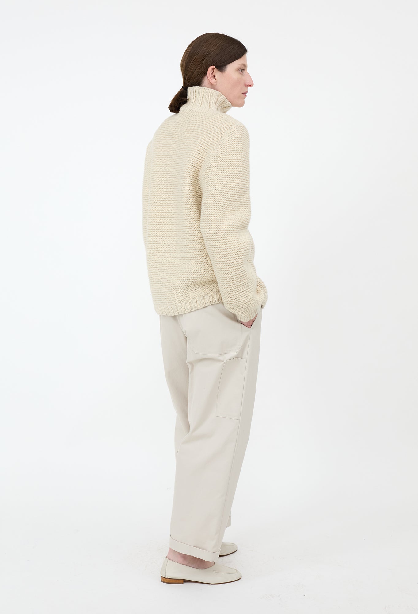 Person wearing a cream sweater and pants on a white background