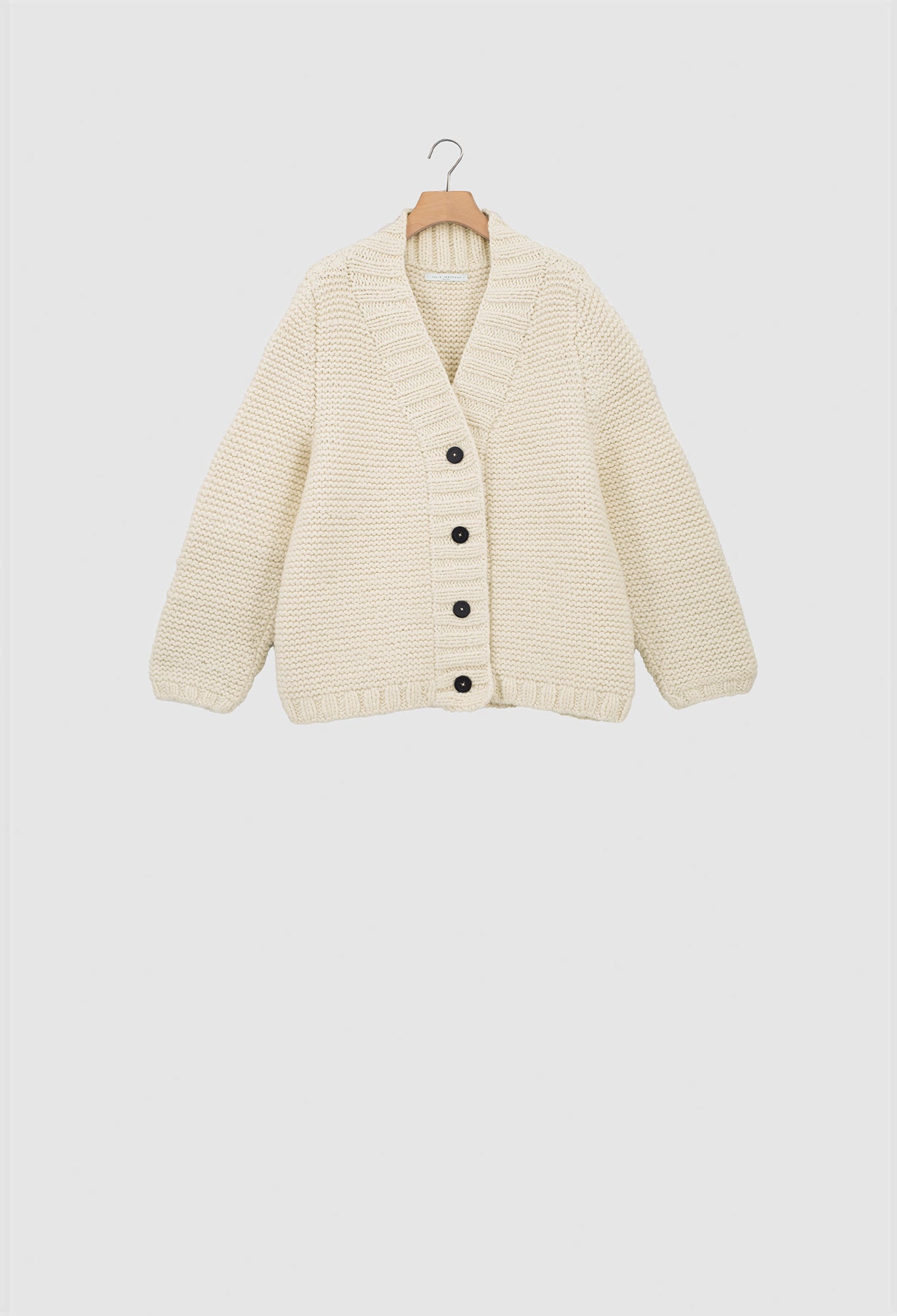Beige cardigan on a hanger against a white background