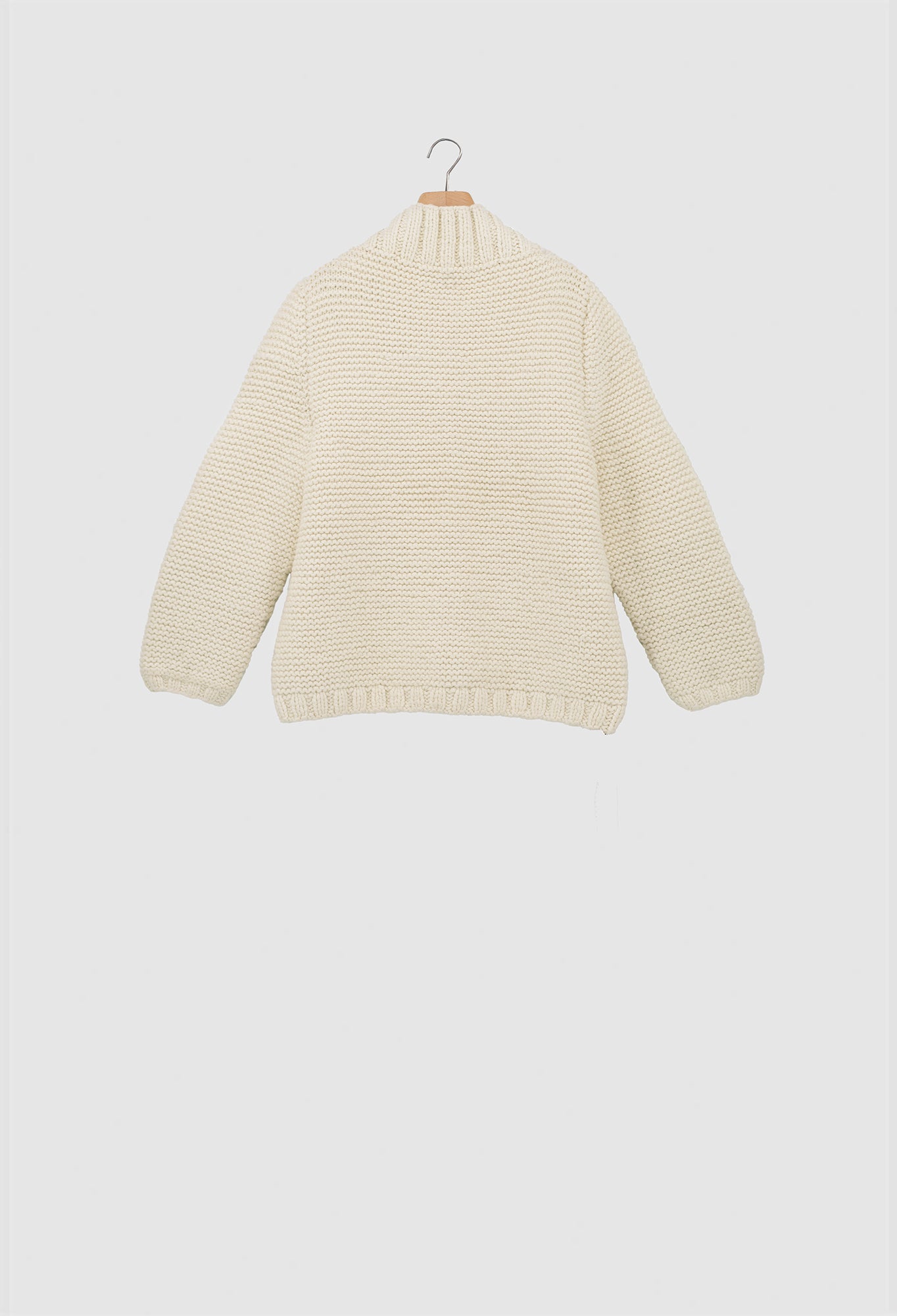 Beige knitted sweater on a hanger against a white background