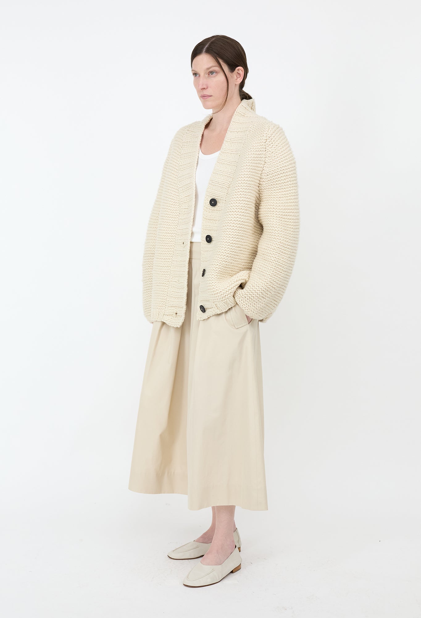 Woman wearing a long cream coat on a white background