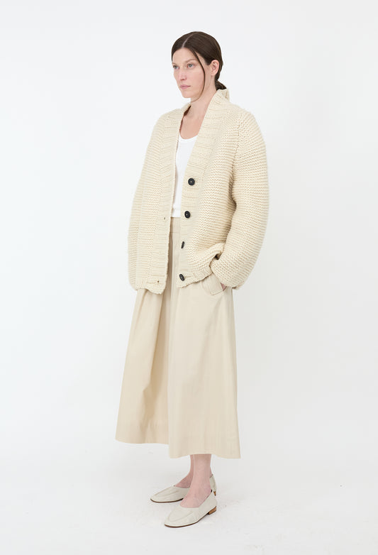 Woman wearing a long cream coat on a white background